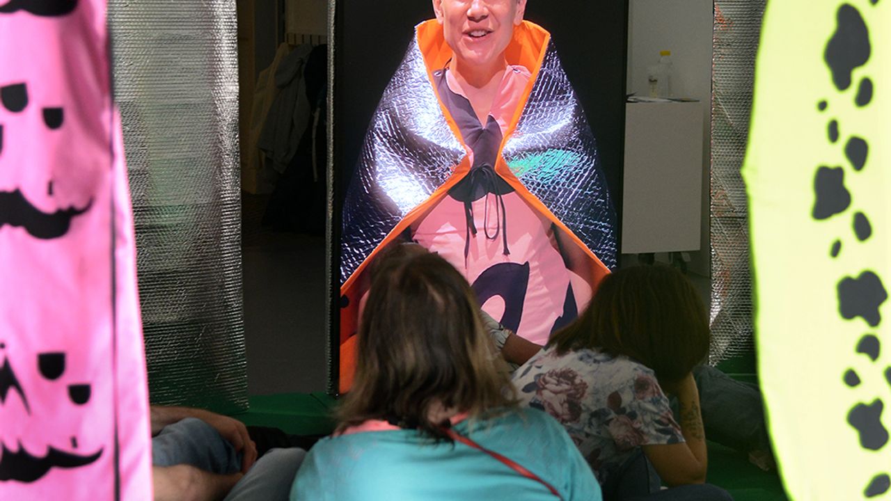 Les visiteur·euses sont assis·es au cœur de l'installation.