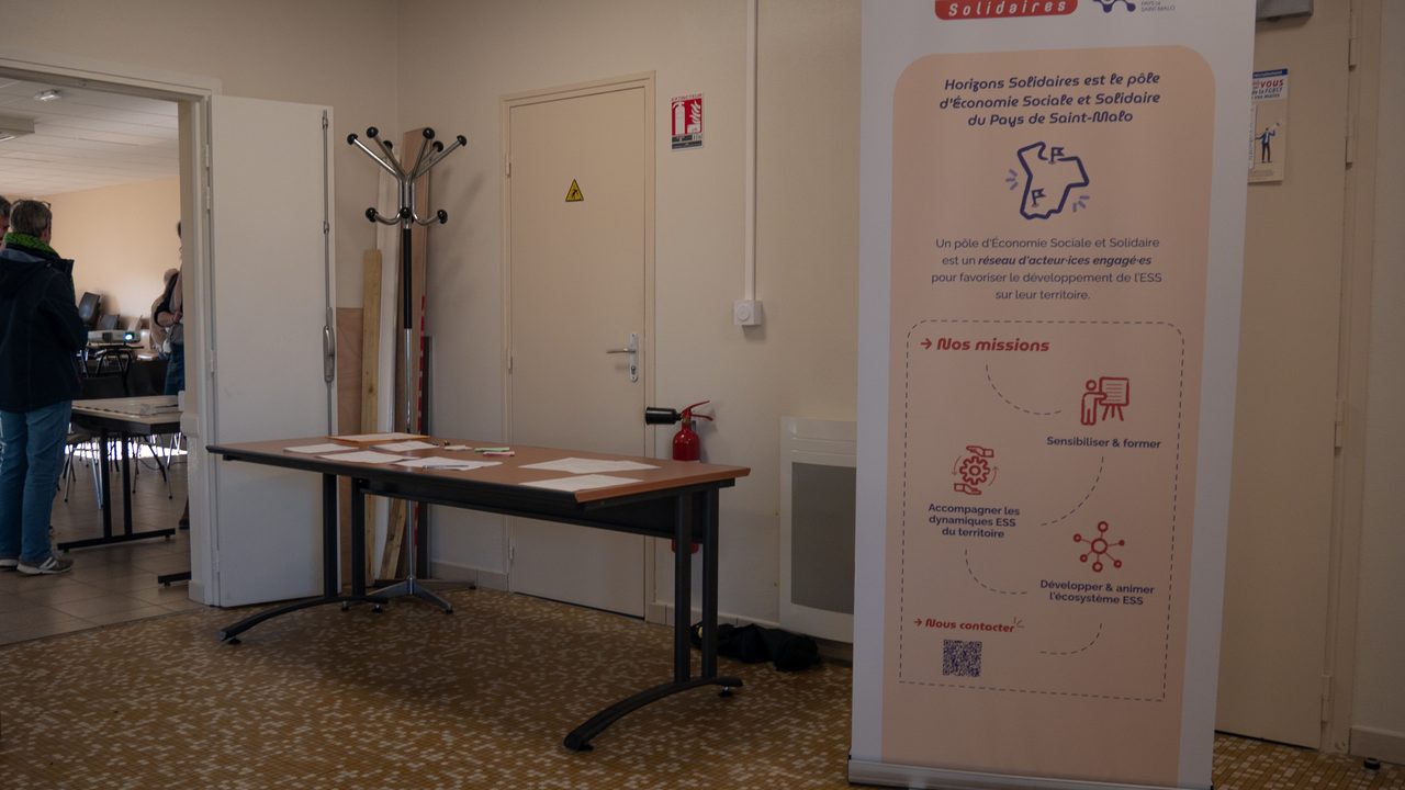 Entrée de la salle de l'Assemblée Générale avec un roll-up présentant les actions d'Horizons Solidaires