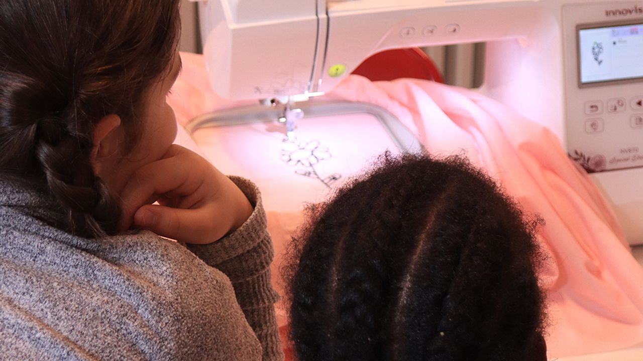 deux enfants regardent la machine faire une broderie