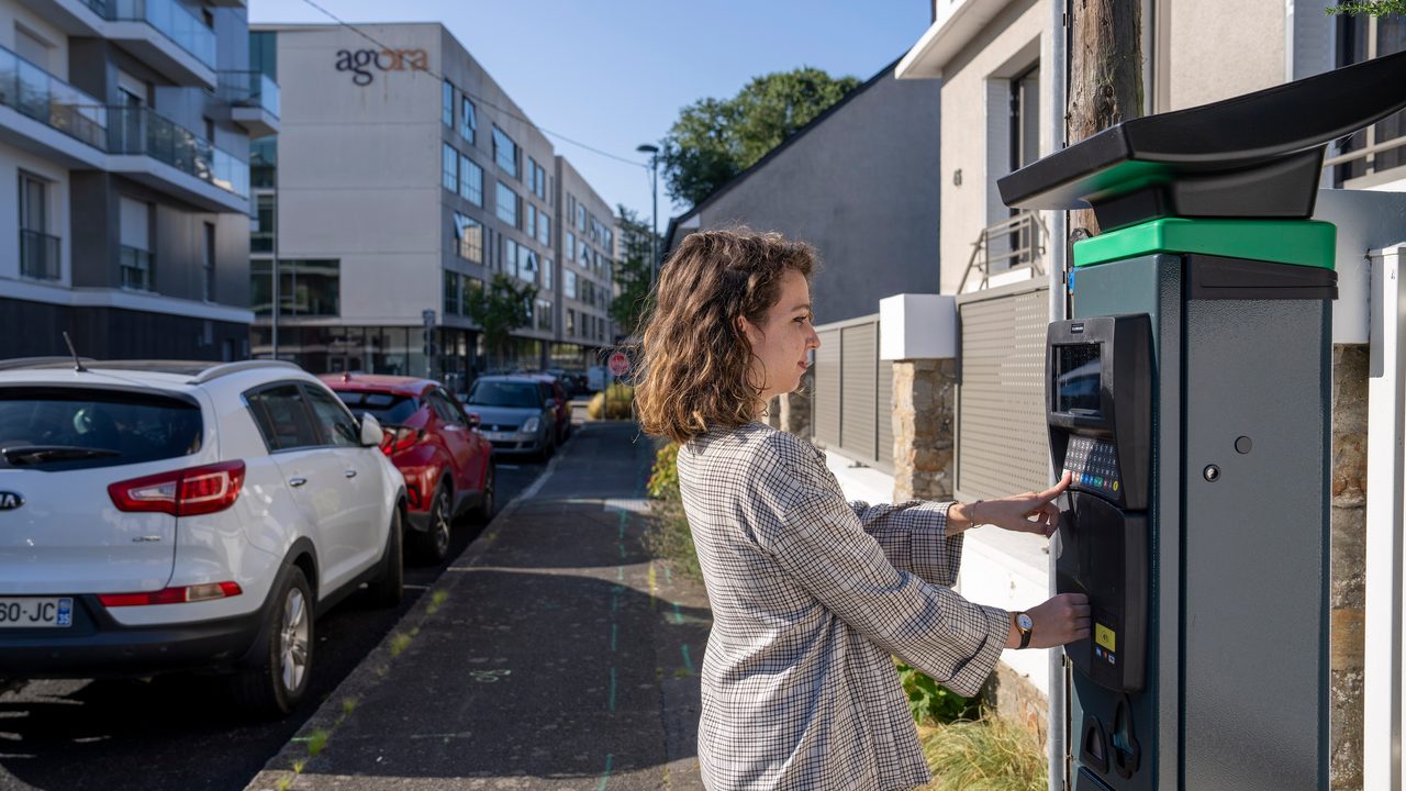 Personne devant un horodateur dans une rue rennaise.