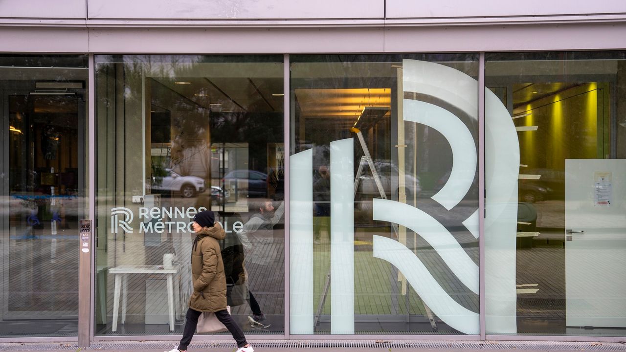 Photo du bâtiment de Rennes Métropole. Deux passants marchent devant l'entrée.