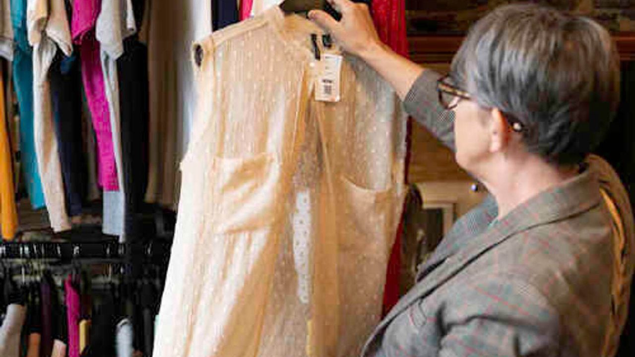 Une femme jauge un haut dans une friperie