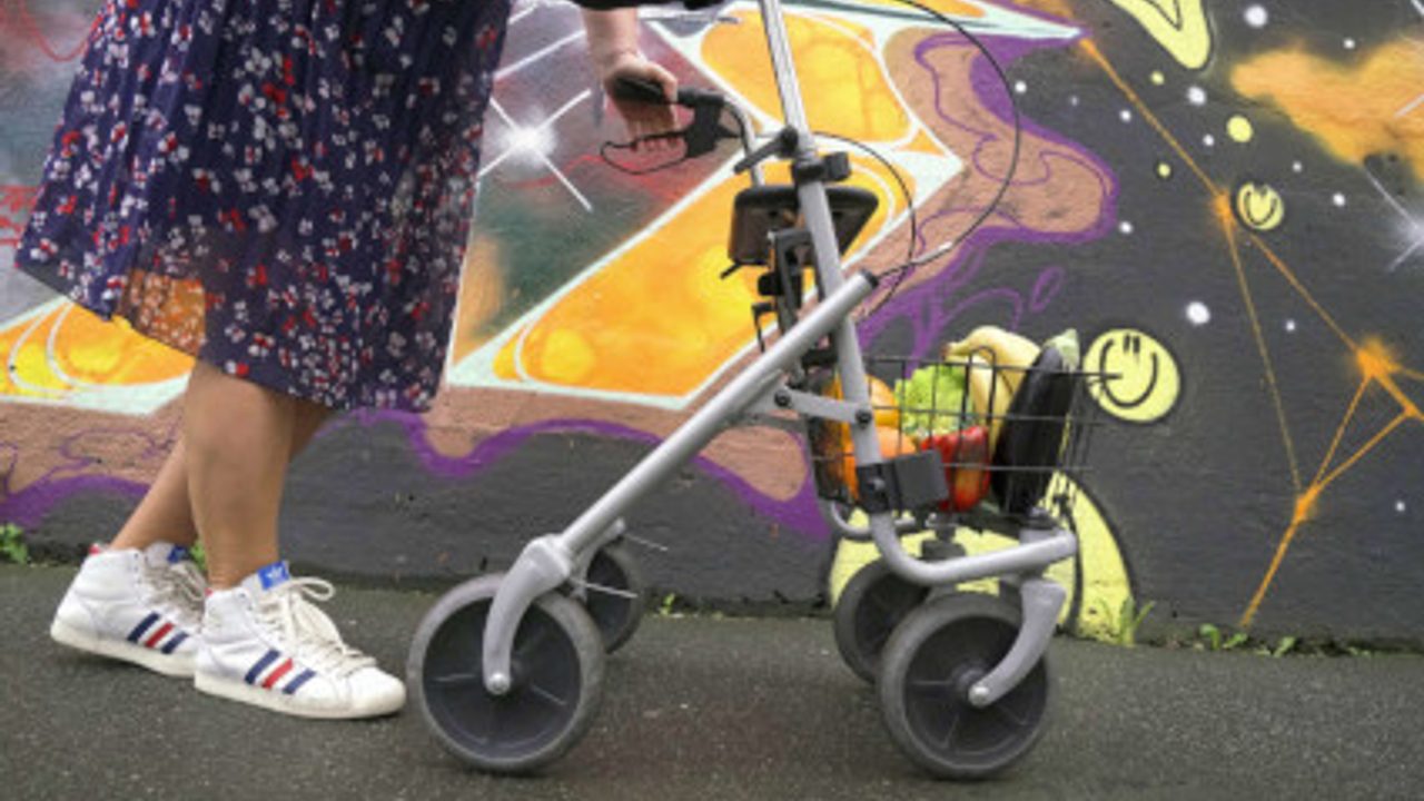 Personne âgée poussant un chariot déambulateur électrique.