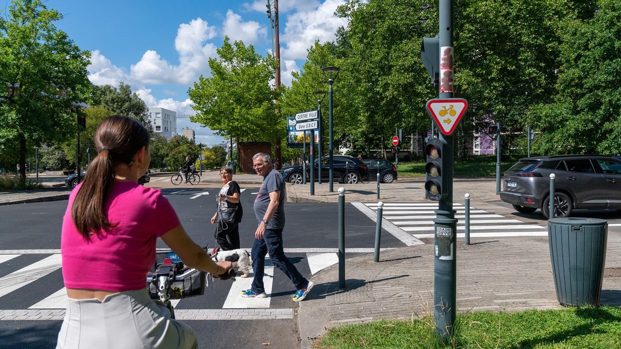 Jeune cycliste arrêtée au feu, des piétons traversent