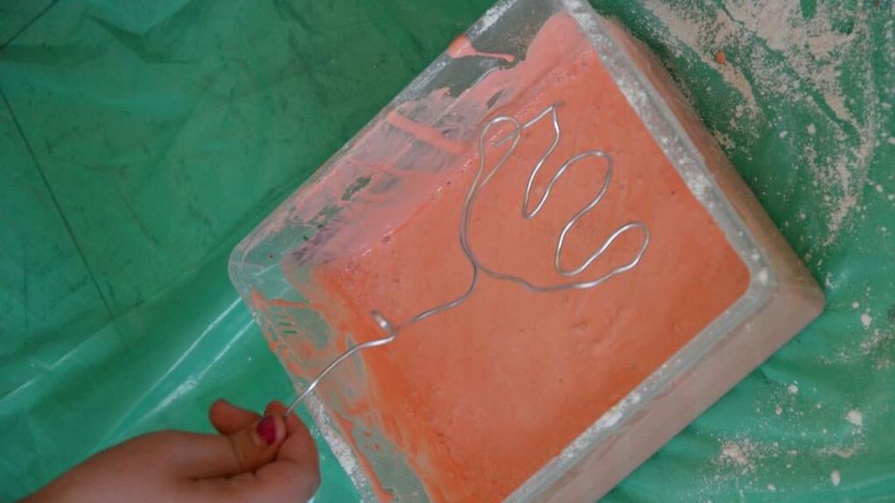 On peut voir une tulipe réalisée avec un fil de fer qui va être plongée dans un bac de peinture rose chair