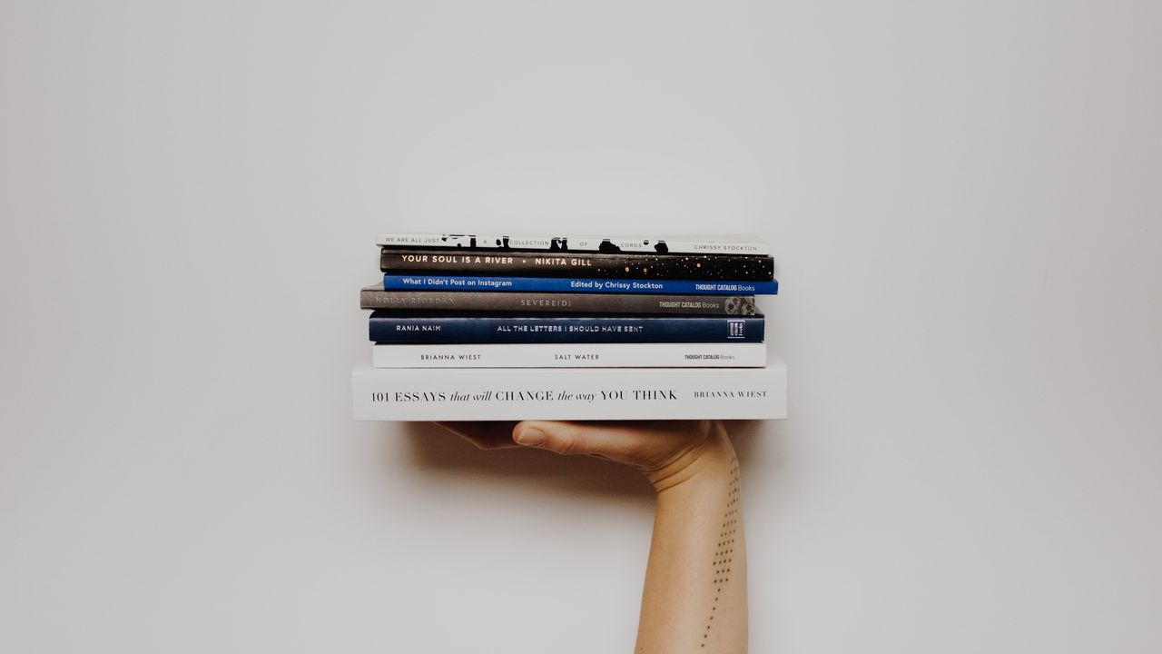 person holding pile of books