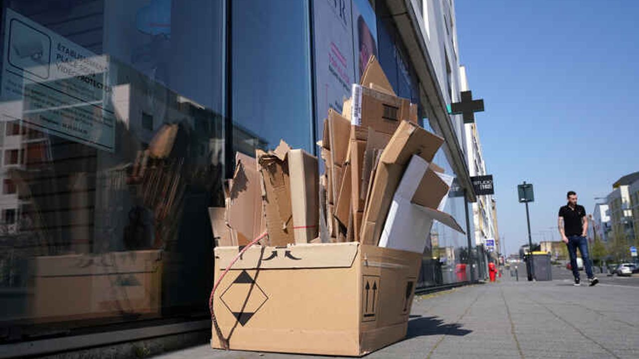 Des cartons de professionnels sont posés sur un trottoir en ville.