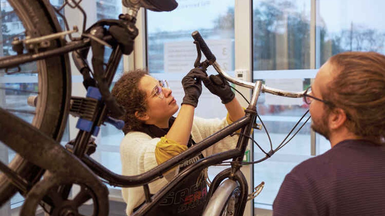 Une femme apprend à réparer son vélo.