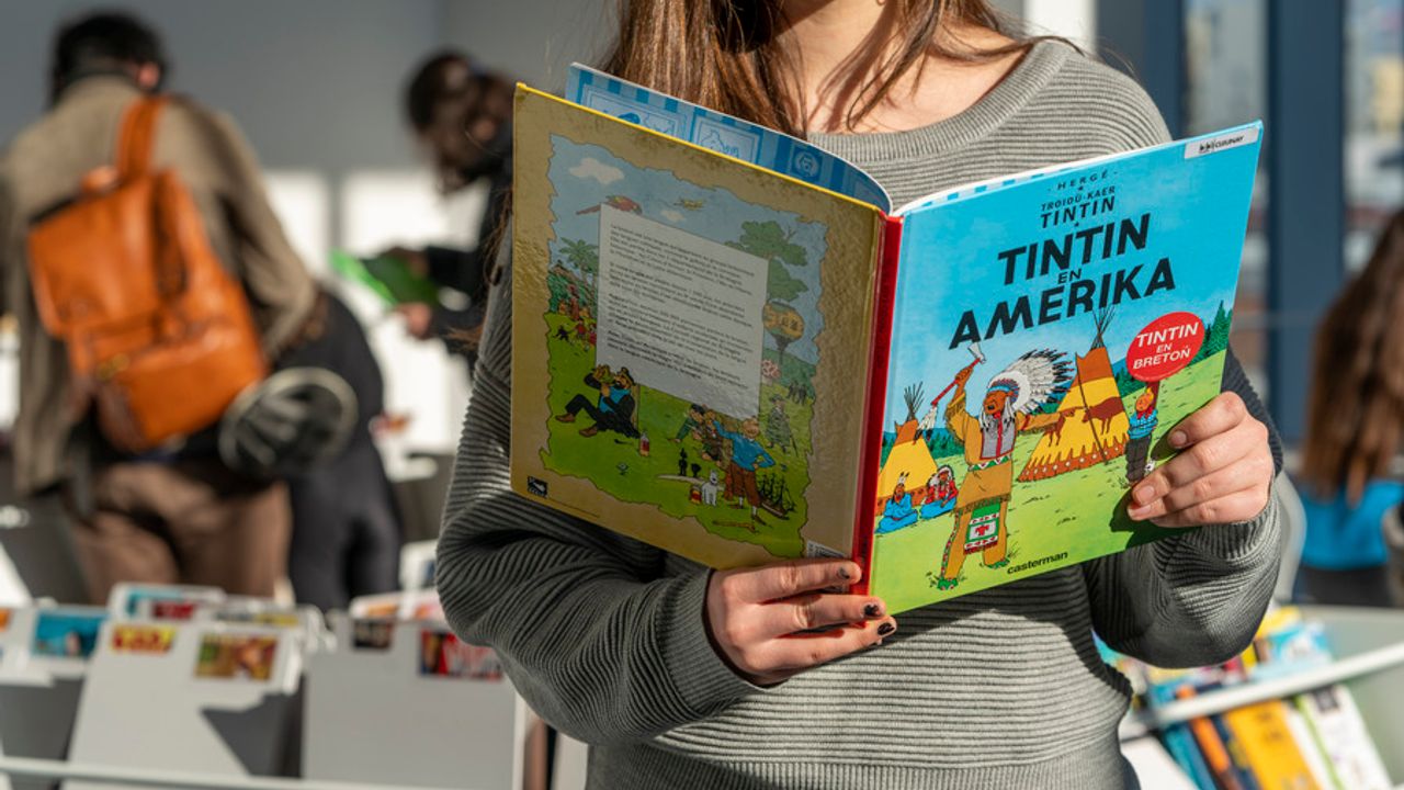 Une femme lit la bande dessinée « Tintin en Amérique » en breton.
