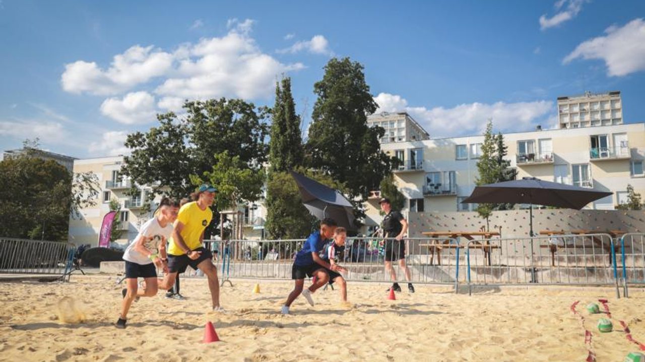 Des jouents font du sport sur un terrain de sable en centre-ville.