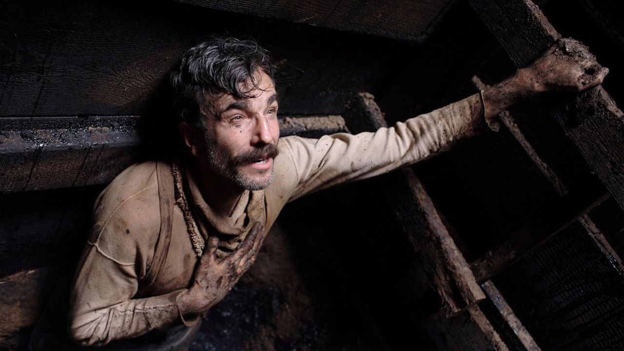 Vue en contre-plongée de l'acteur Daniel Day-Lewis, dans une fosse remplie de boue, à moins qu'il ne s'agisse d'autre chose...