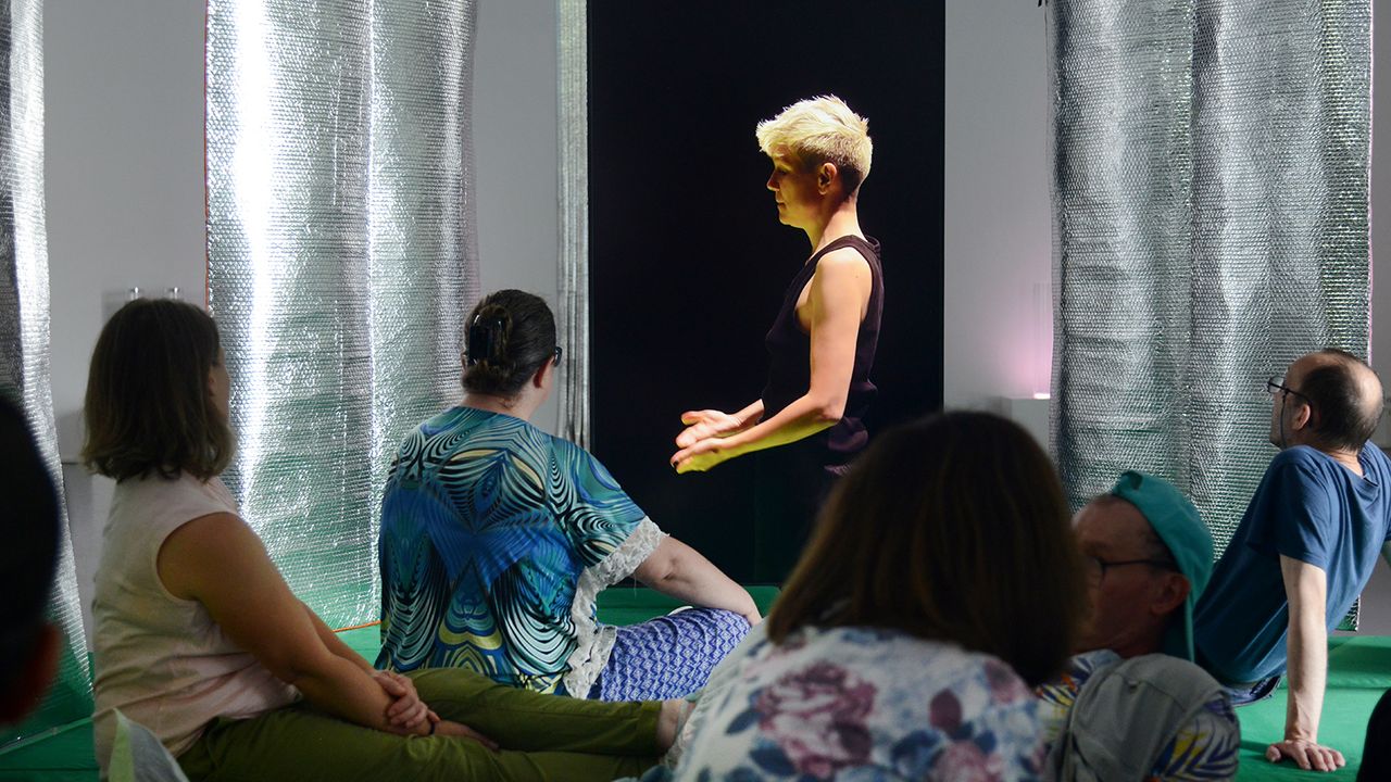 Le groupe de visiteur regarde une vidéo-performance de l'artiste.