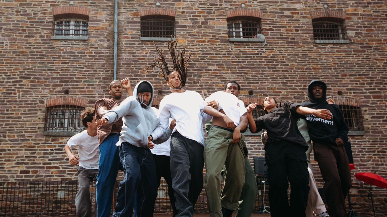 Des danseurs de hip-hop sur scène devant le mur extérieur de la prison