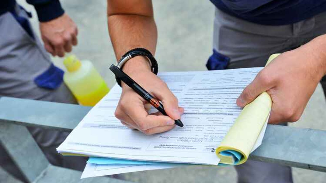 Gros plan sur la main d'un contrôleur remplissant un rapport papier.