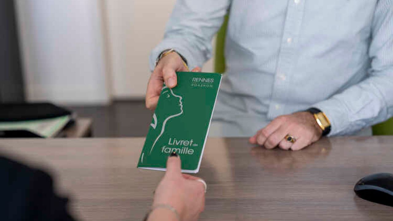 Une femme reçoit son livret de famille des mains d'un agent de l'état civil.