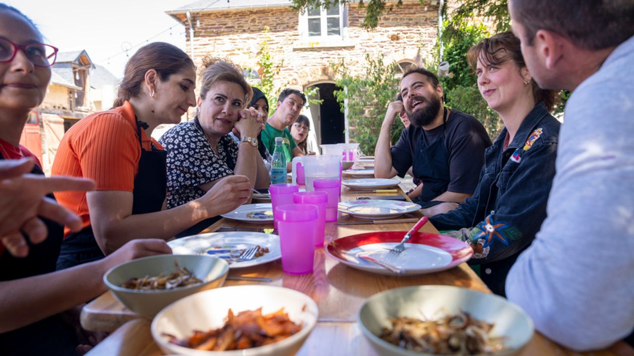 Des personnes autour d'une table, s'apprêtent à déjeuner.