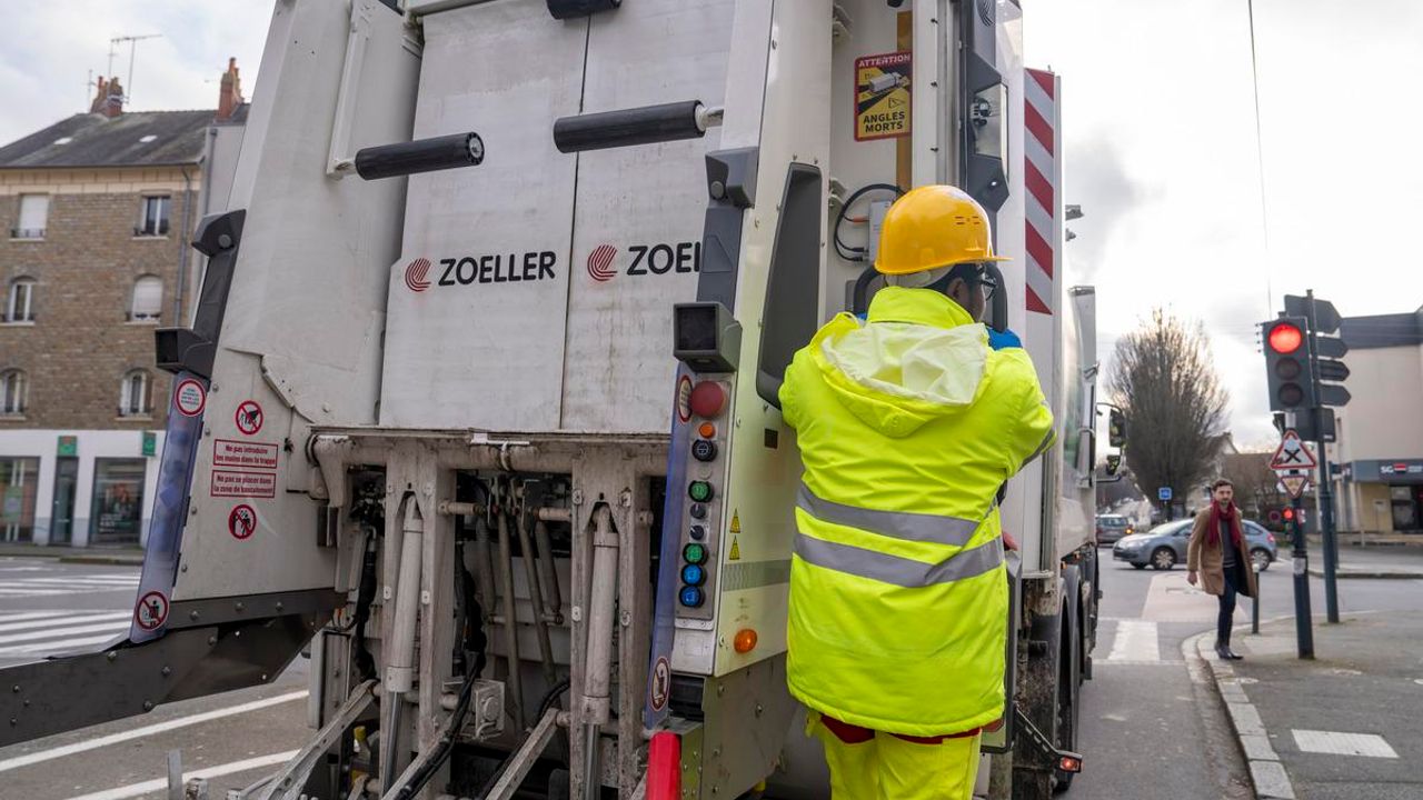Une personne en tenue fluorescente sur un camion de collecte de déchets