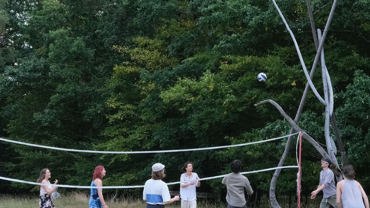 Group of people playing volleyball outside in a field