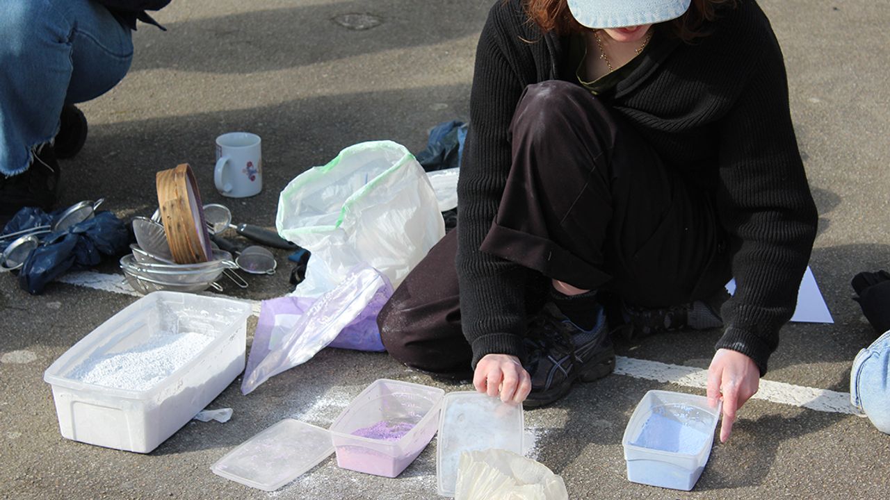 Margot est accroupie et manipule les pigments et la craie en poudre.