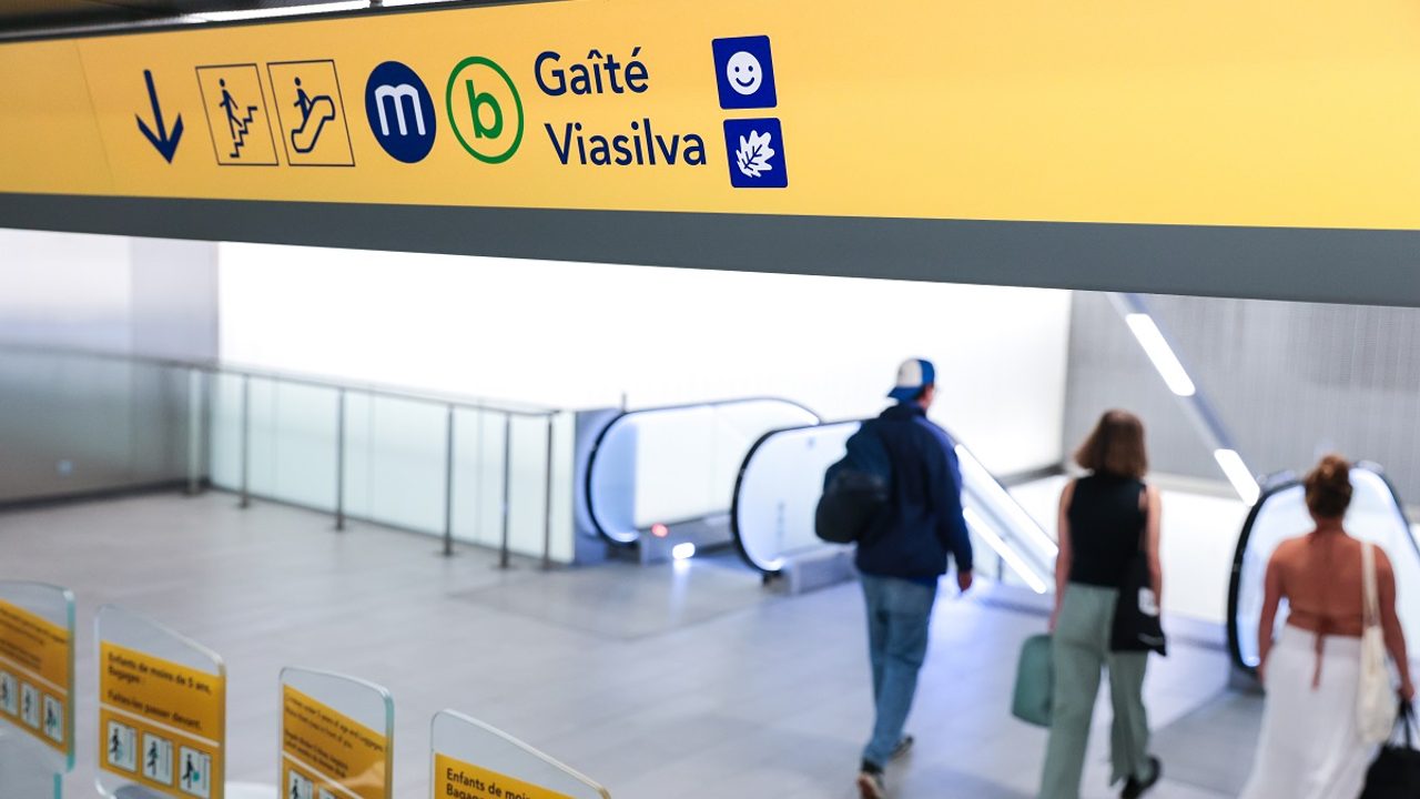 Photo dans le métro d'un panneau d'information de direction, au dessus des valideurs, avec la nouvelle signalétique.