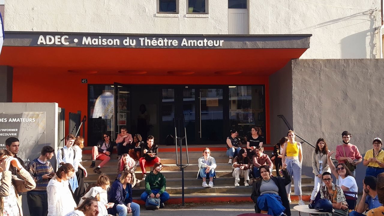 vue de l'extérieur du batiment de l'Adec avec du public assis et debout 