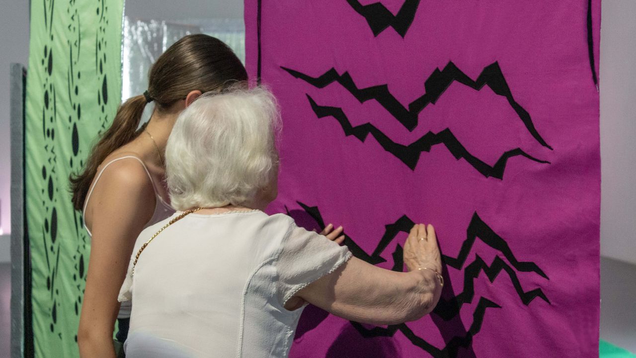 Une médiatrice guide une visiteuse non-voyante.