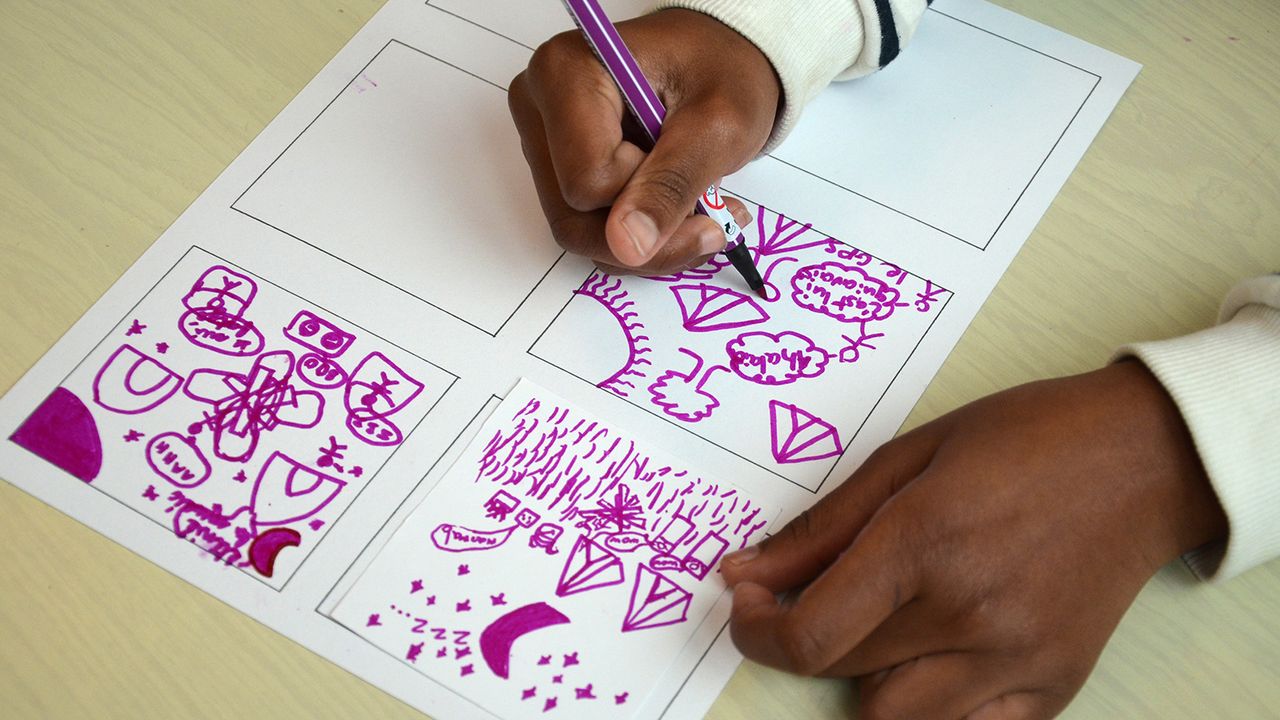 Une enfant dessine au feutre violet dans les cases.