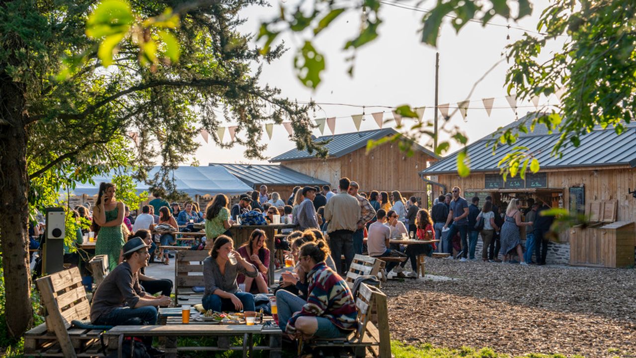 Plusieurs groupes de personnes attablés à la guinguette de la Basse Cour. 