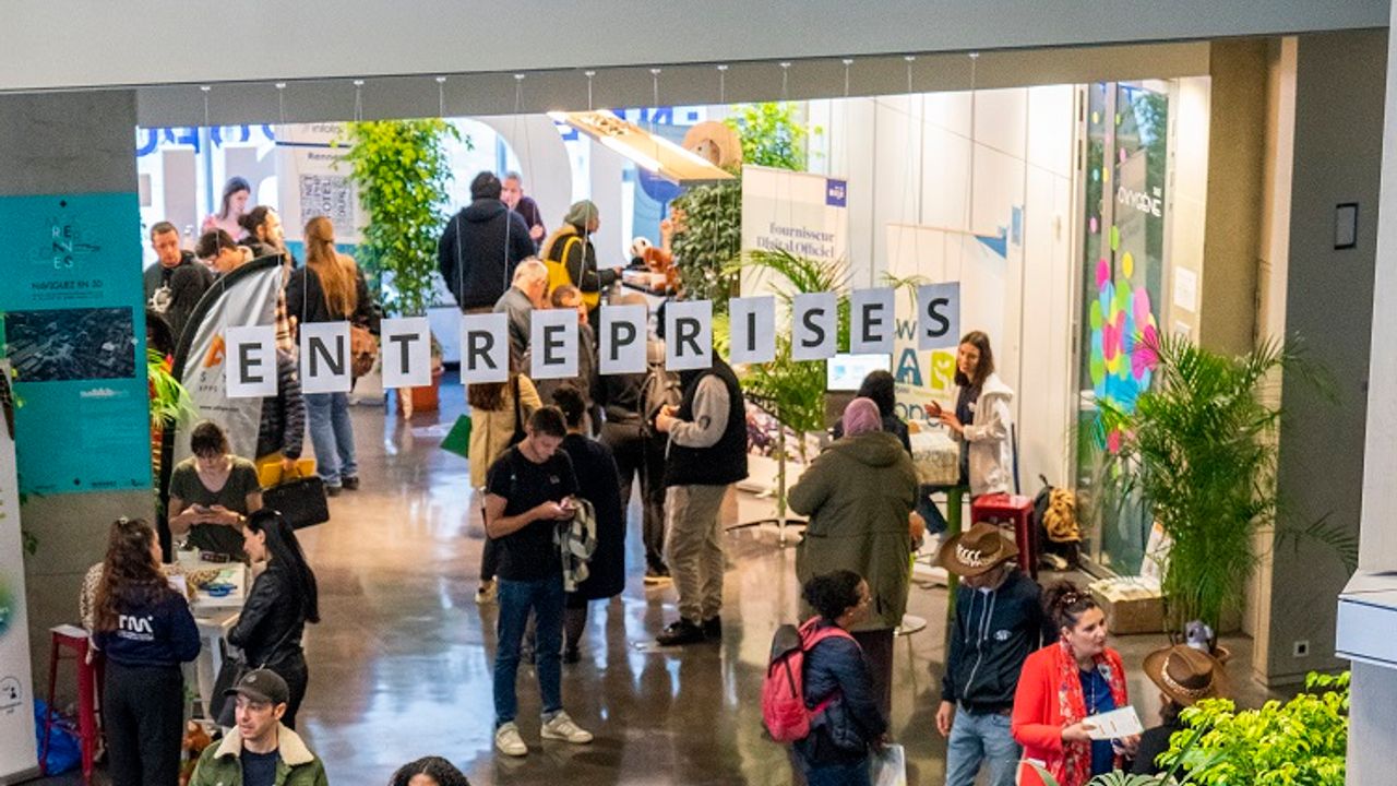 Visiteurs dans un salon des métiers du numérique. avec les lettres entreprises accrochées