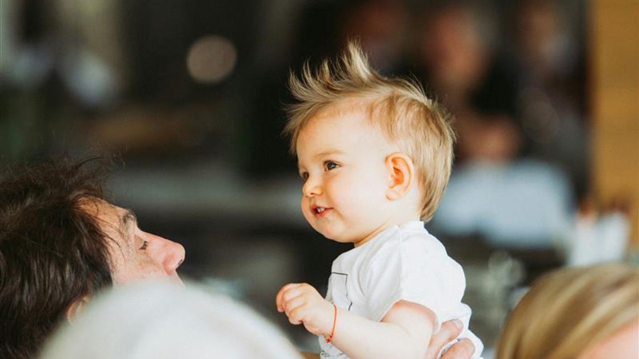 Un enfant est tenu en hauteur dans les bras d'une personne 