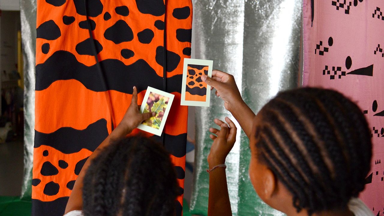 Deux enfants comparent les photographies des cartes avec les œuvres exposées.