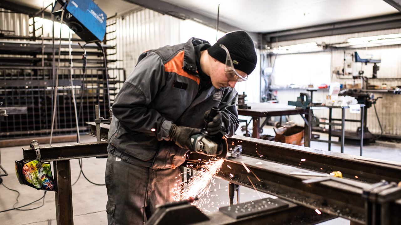 Salarié qui découpe un bloc de métal chez l'Atelier de la Verrière