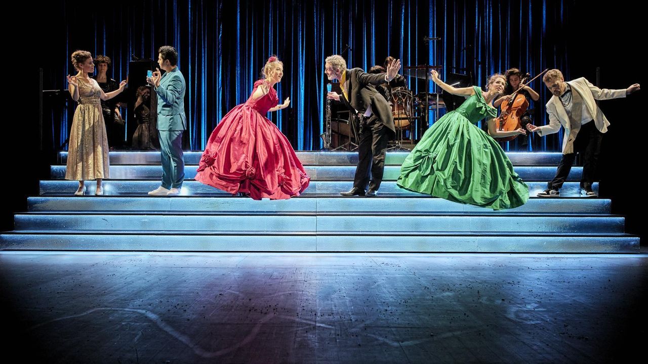 Sur une scène, des femmes en robe crinoline et des hommes dansent