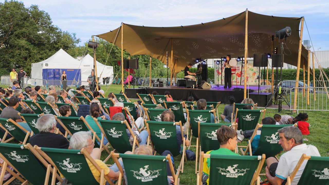 Des personnes sur des transats qui regardent la scène où une femme chante