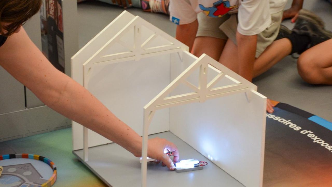 La médiatrice culturelle Amandine Braud place une oeuvre miniature dans l'espace d'exposition miniature du jeu collaboratif Rejouer La Criée, installé dans La Criée. 