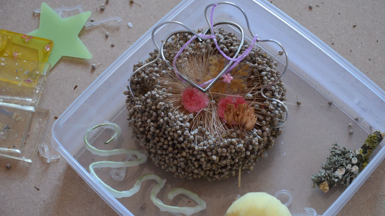 Les enfants ont réalisé une installation des œuvres de Lucie pendant qu'elle parlait. Un coeur en fil de fer est entremêlé avec des fils violets, des fleurs séchées, un champignon de mousse, des roses et des serpents de paraffine.