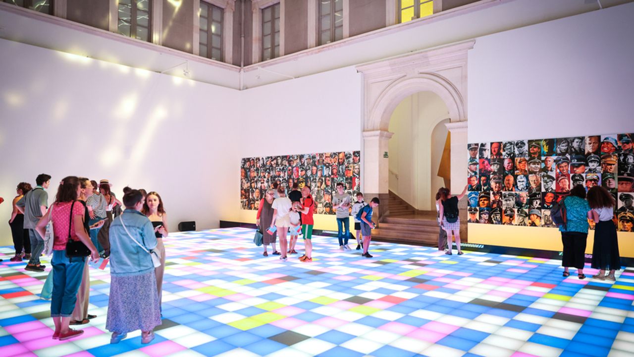 Grande salle d’exposition dans l’entrée du Musée avec des visiteurs qui découvrent Exporama. Le sol est pour l’occasion composé de cubes lumineux comme la fièvre du samedi soir