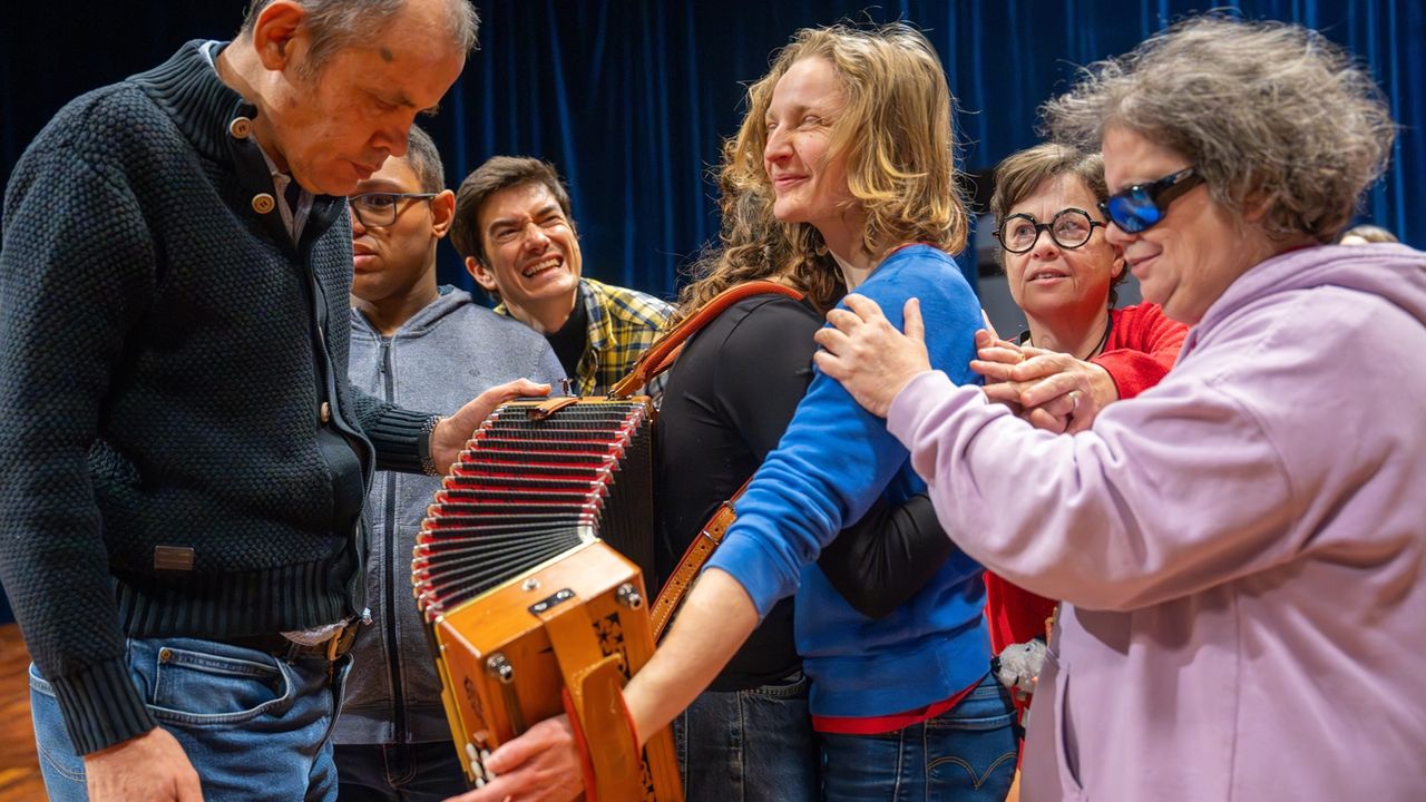 Au centre de l'image, une joueuse d'accordéon entourée de personnes malvoyantes et du chorégraphe Massimon Fusco au dernier plan. La bonne humeur règne.