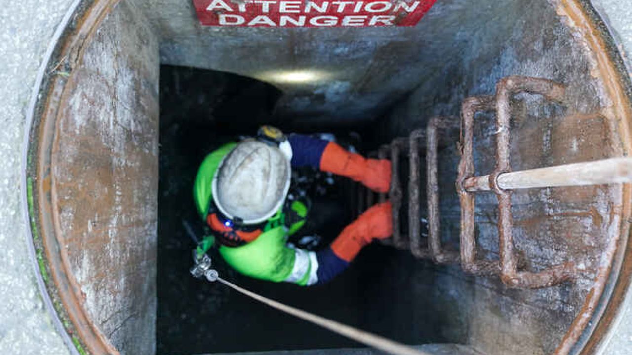 un égoutier descend à l'échelle dans un égout
