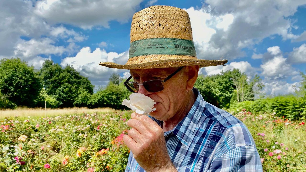 gros plan sur Michel Adam qui renifle une rose