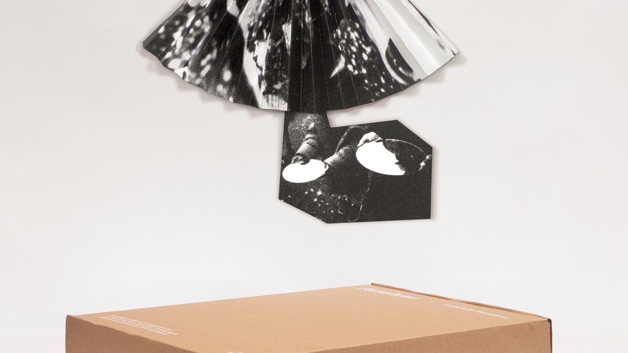 En arrière plan le multiple de Gabrielle Manglou accroché au mur. Au premier plan, la boite en carton sérigraphiée.