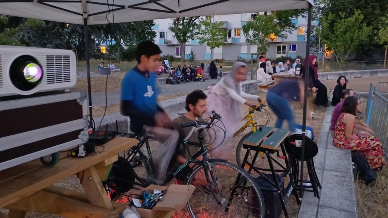 Un projecteur en premier plan, et des cyclistes pédalant