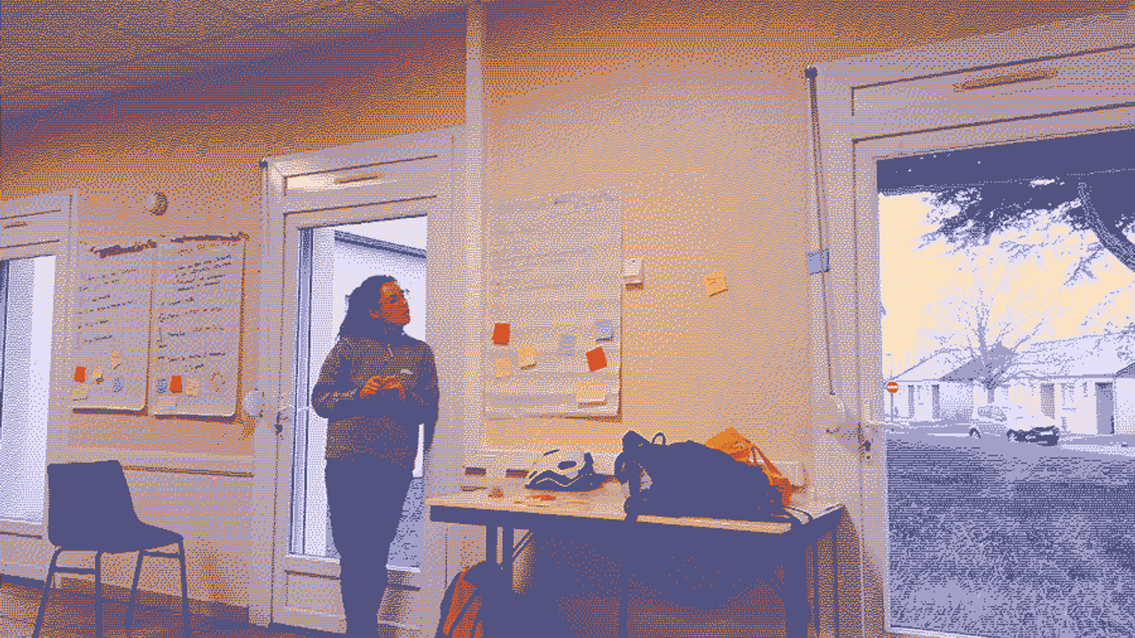 Une personne se tient devant une feuille de paper board remplie de post-it