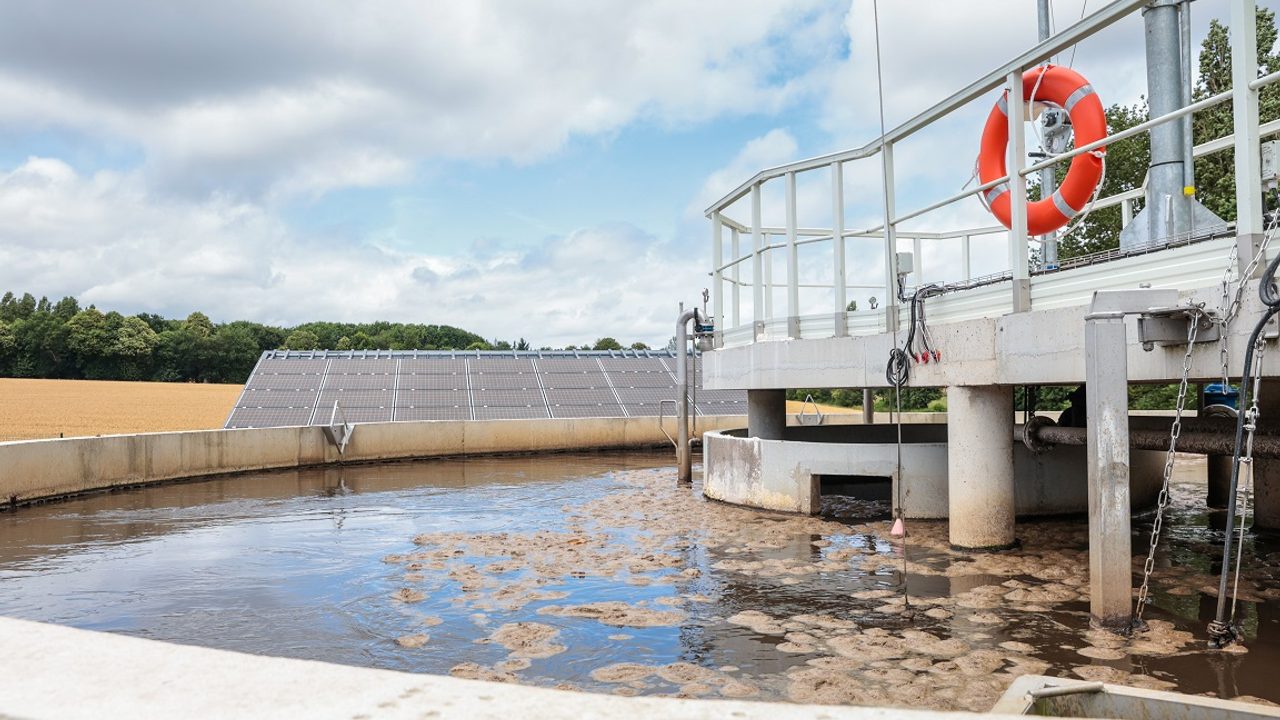 Photo de la nouvelle station d'épuration de Romillé. Au premier plan, un bassin d'aération, au deuxième plan les panneaux photovoltaïques installés sur le site.  