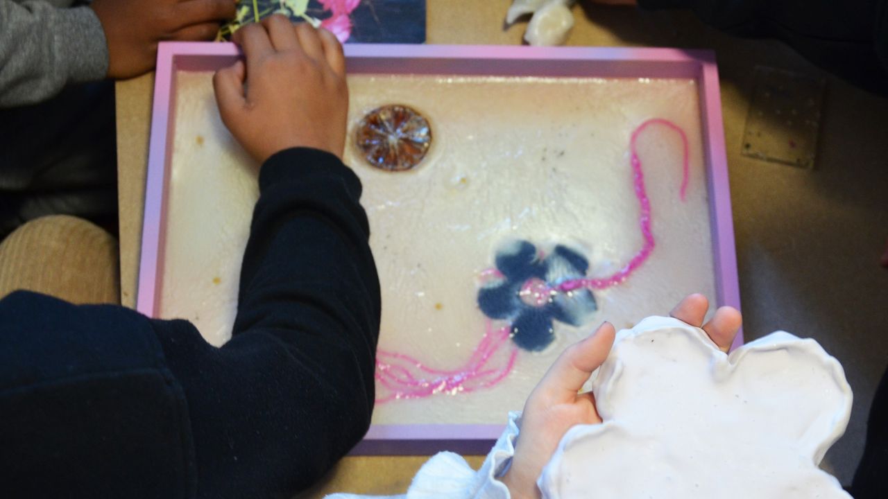 Les élèves de CE2 de l'école Jean Moulin découvrent les œuvres de l'artiste Lucie Férézou dans son atelier. Sur cette photo, ils et elles manipulent des matières brillantes, gluantes, séchées ou naturelles avec lesquelles travaille l'artiste. 