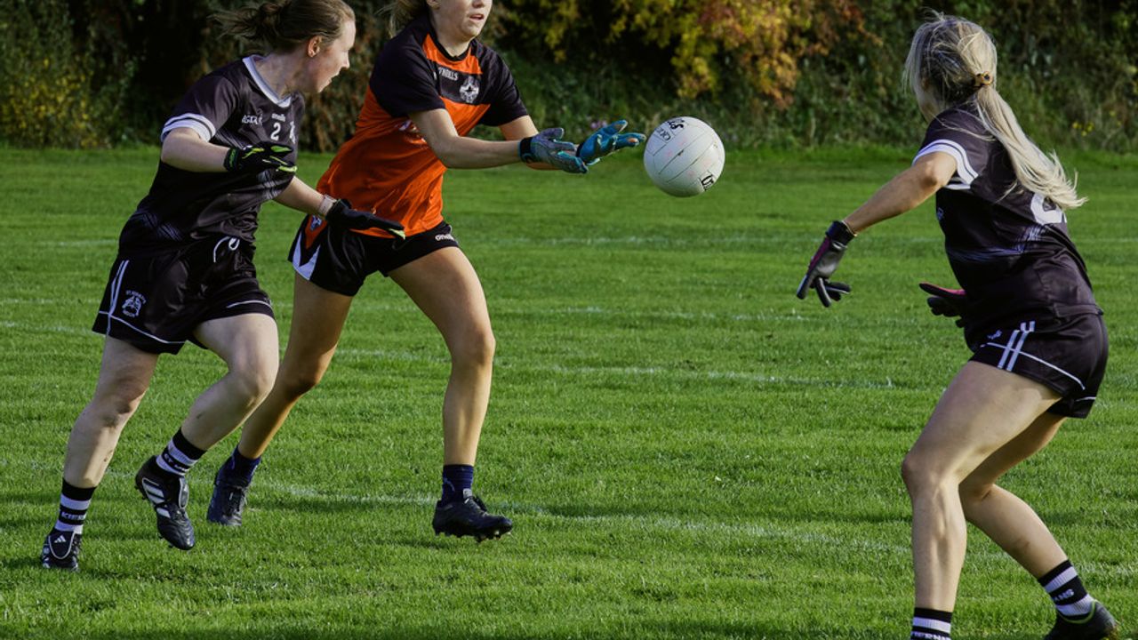 3 jeunes filles pratiquant du foot gaélique sur un terrain