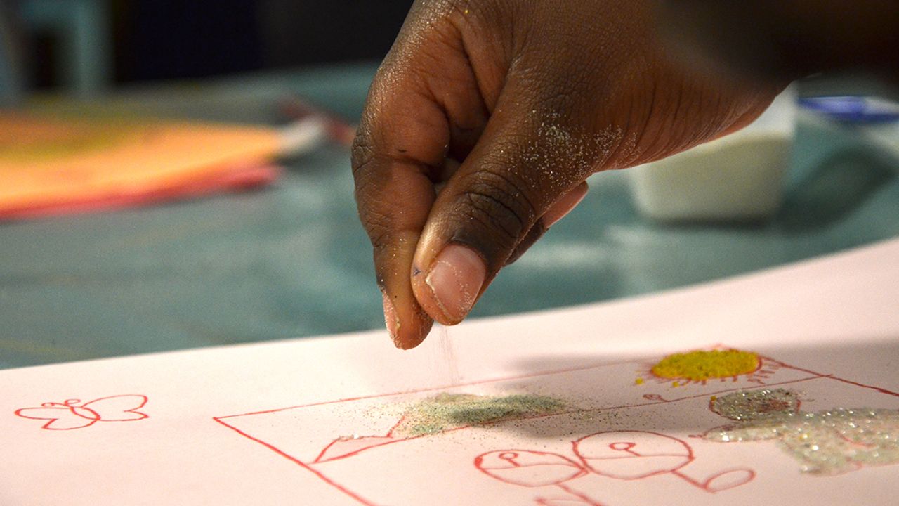 Une élève saupoudre son dessin de paillettes naturelles.