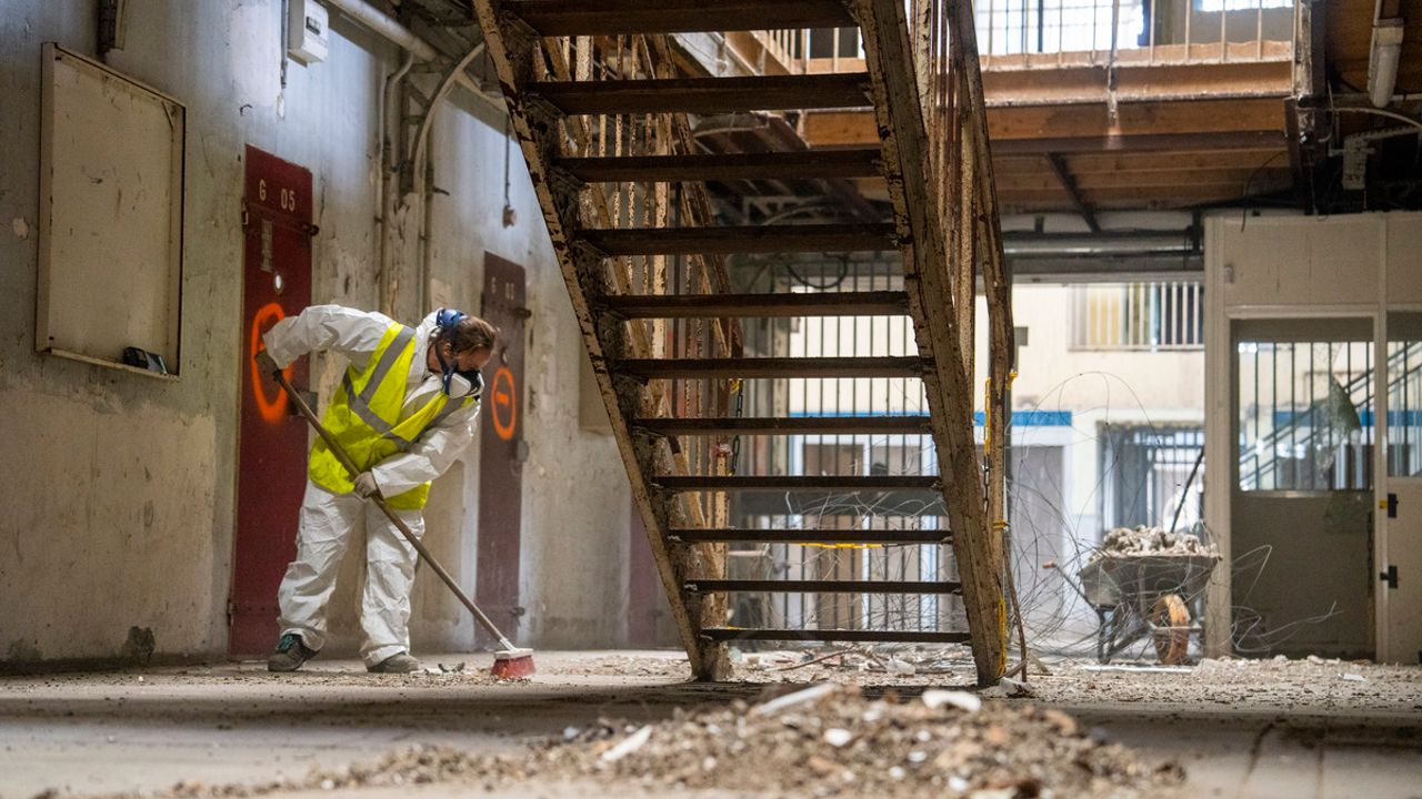 Agent passant le balai devant un petit monticule de gravats