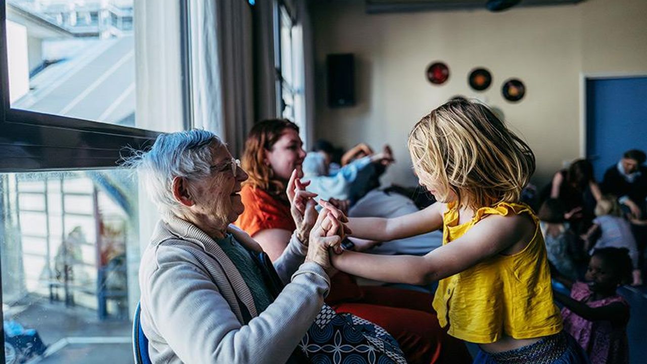 Une personne agée danse avec une enfant