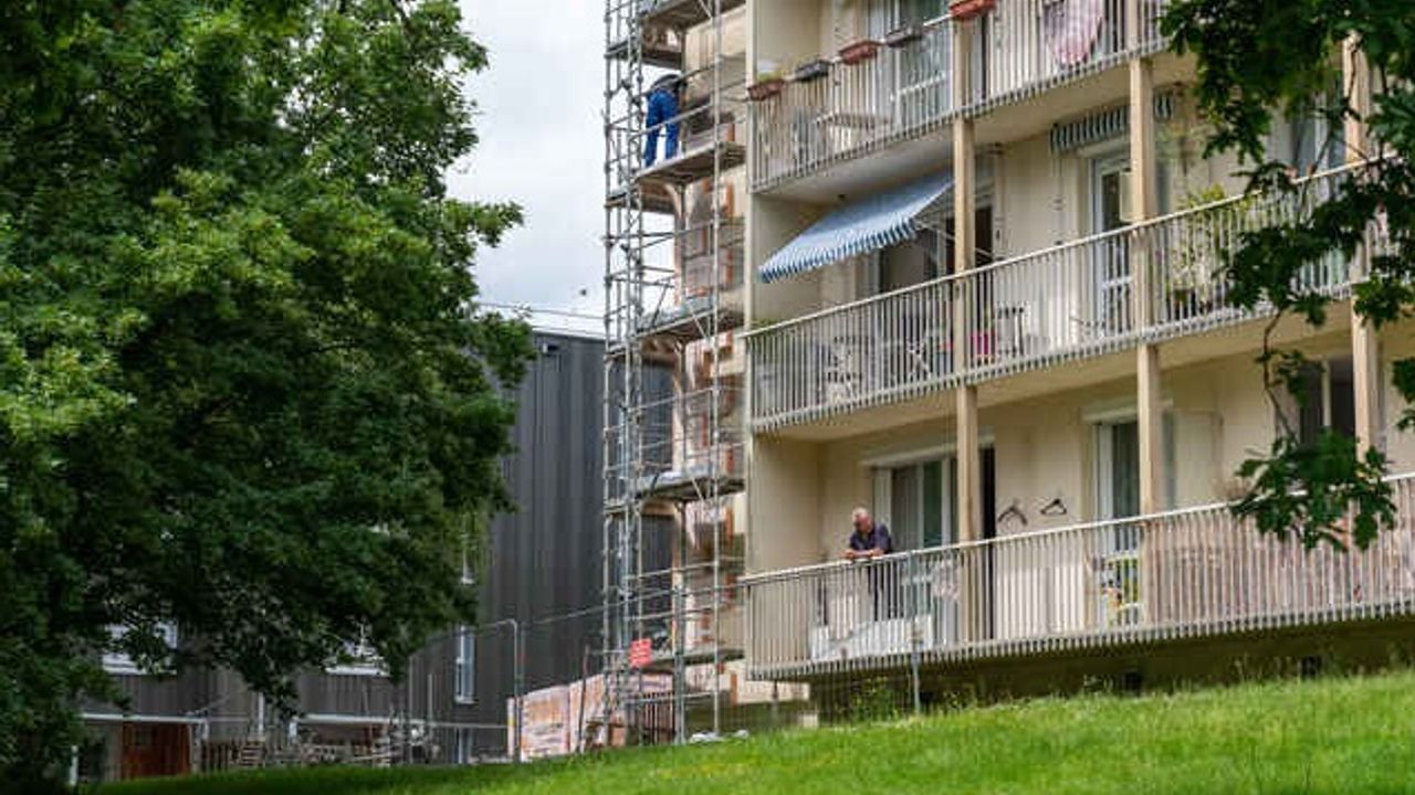 Un échafaudage est posé au sol devant un immeuble sur un espace vert
